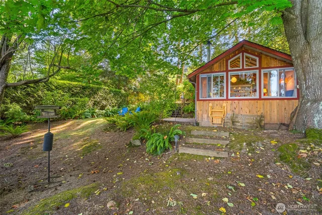 a pathway of a house with potted plants and large trees