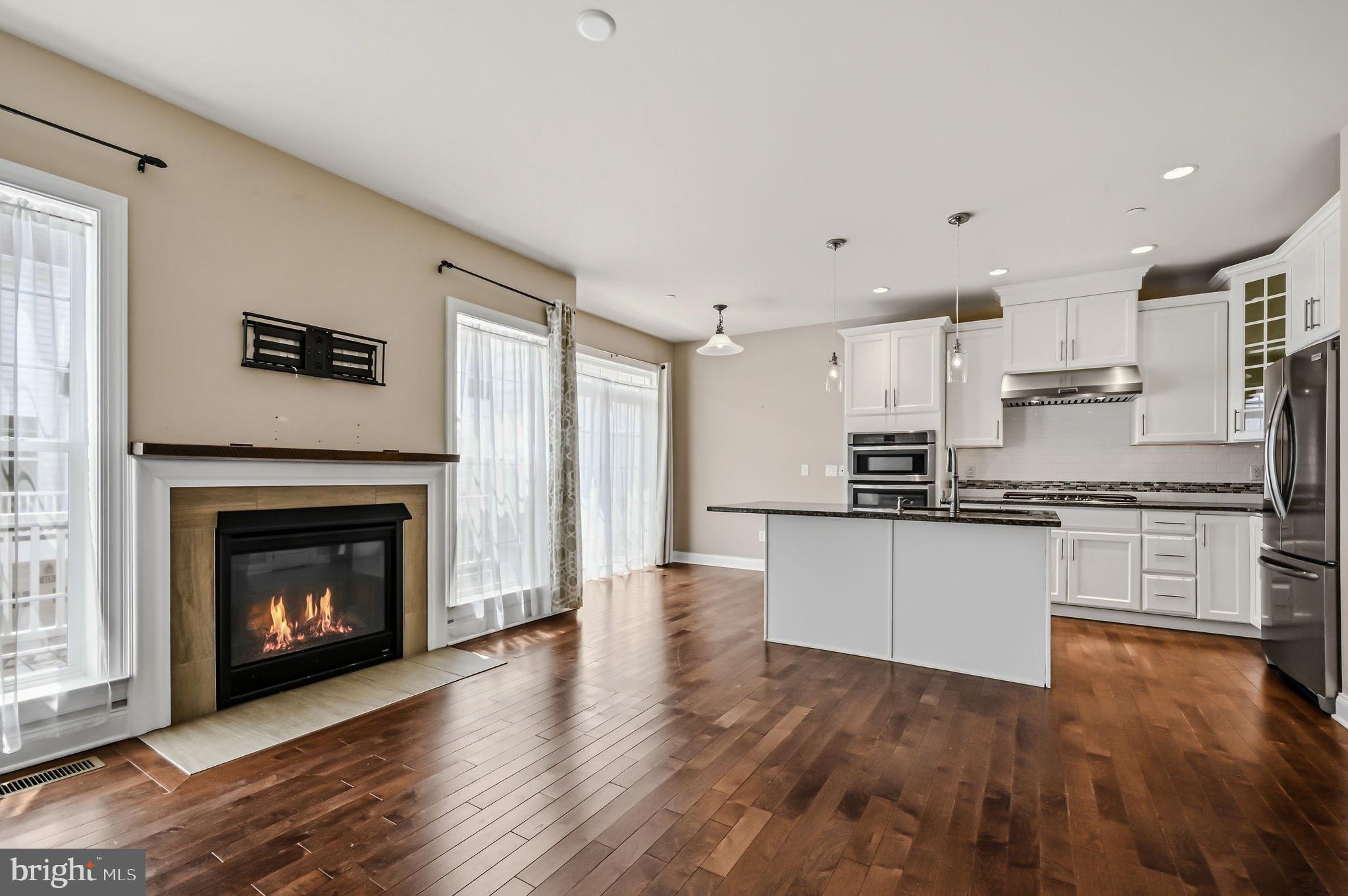 208 Jackdaw Alley, Unit 208 Springfield, PA 19064 - Photo 14 of 49 a kitchen with stainless steel appliances granite countertop a stove top oven a sink dishwasher and a fireplace with wooden floor