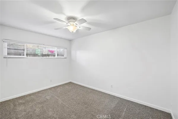 an empty room with a window and a chandelier fan