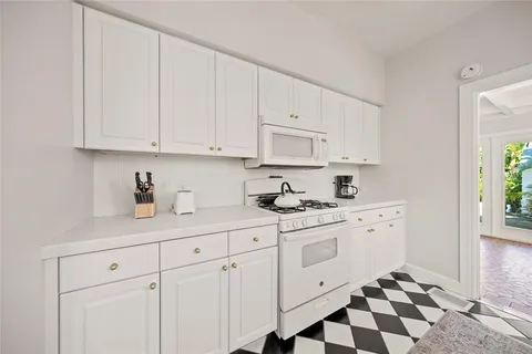 a kitchen with white cabinets and sink