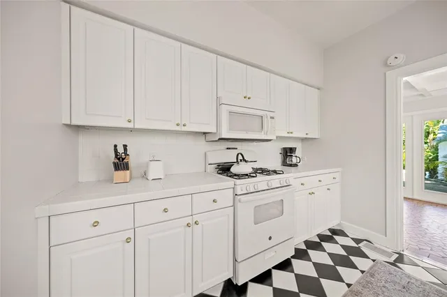 a kitchen with white cabinets and sink