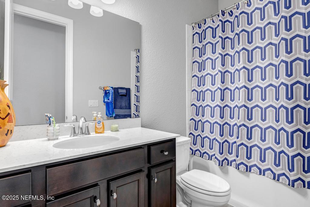 323 Glenneyre Circle St. Augustine, FL 32092 - Photo 36 of 53 a bathroom with a sink a toilet and shower curtain