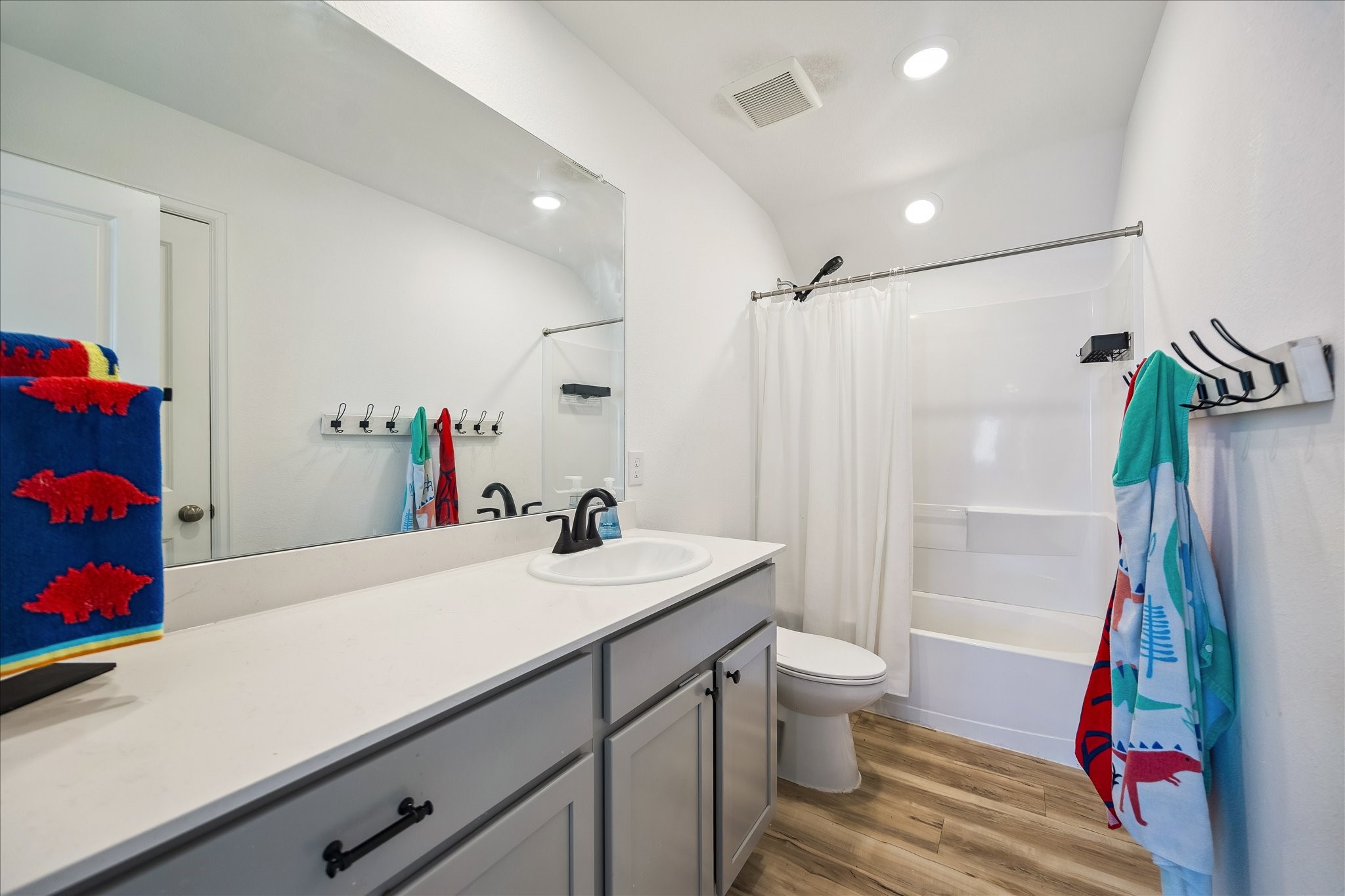 3812 Moss Hl Road Rosenberg, TX 77469 - Photo 19 of 20 Shared bathroom features a clean, modern design with a spacious vanity, large mirror, and sleek fixtures. It includes a combined shower and bathtub complemented by light wood-style flooring and bright lighting.