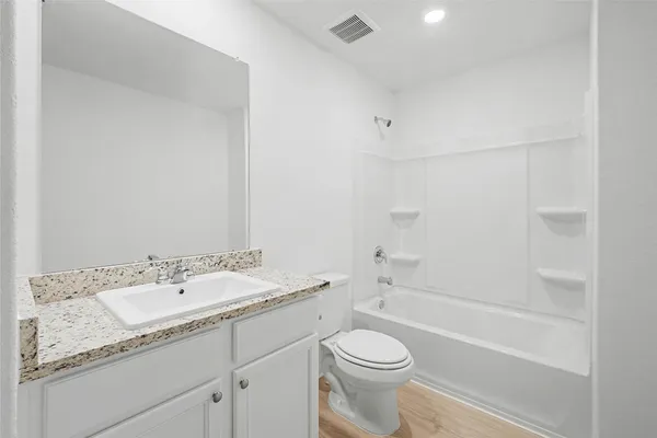 a bathroom with a granite countertop sink a toilet and bathtub