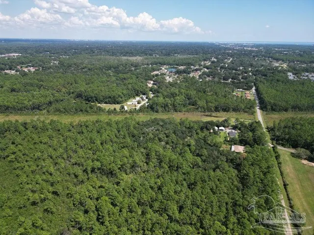 an aerial view of residential houses with outdoor space and trees