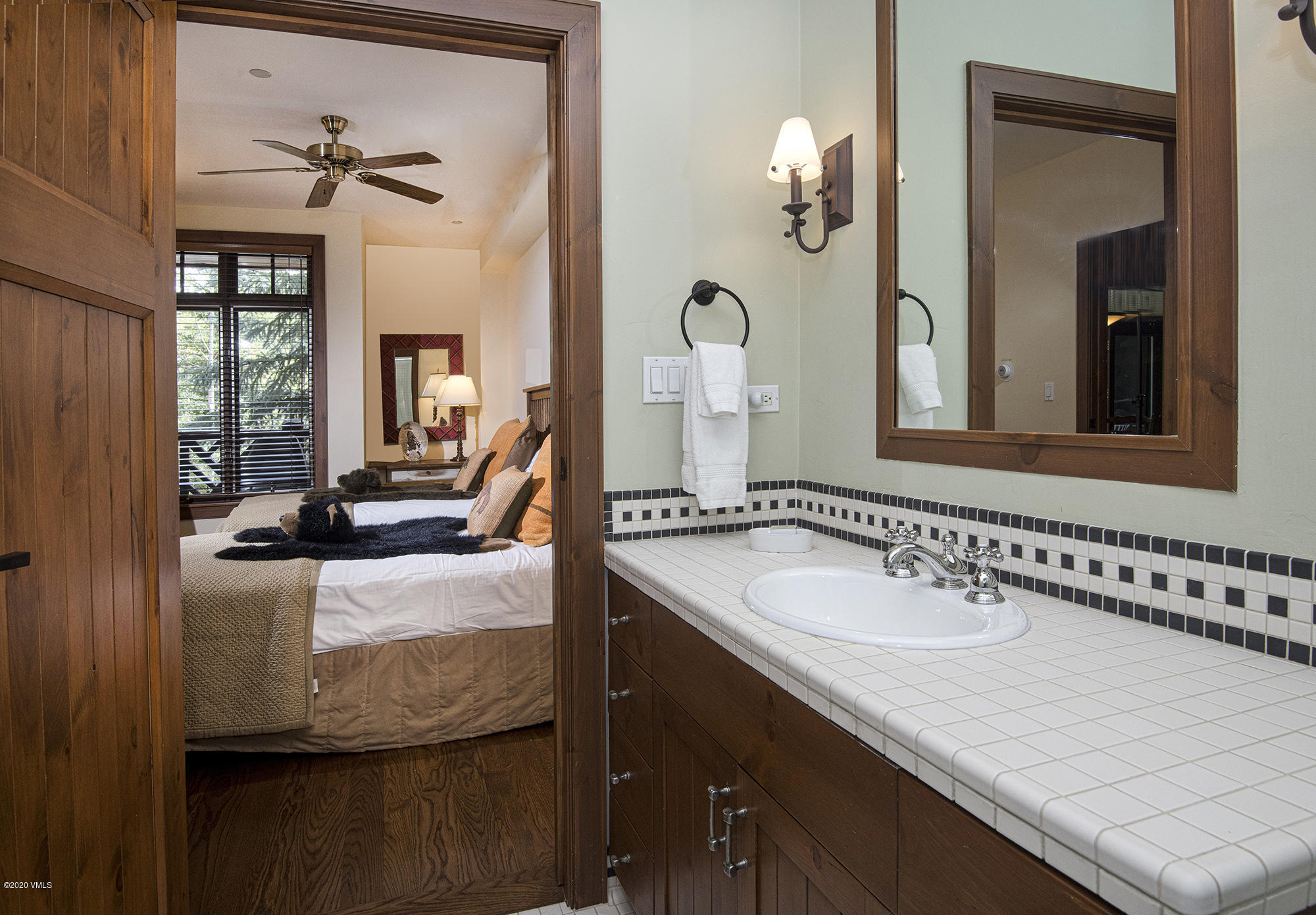 180 Daybreak Ridge Road, Unit 409 Avon, CO 81620 - Photo 19 of 47 a en suite bathroom with a granite countertop sink a mirror and a vanity