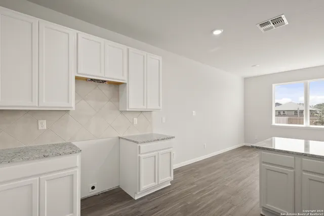a kitchen with granite countertop white cabinets and a sink