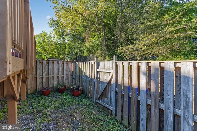 a view of a backyard with wooden fence and large trees