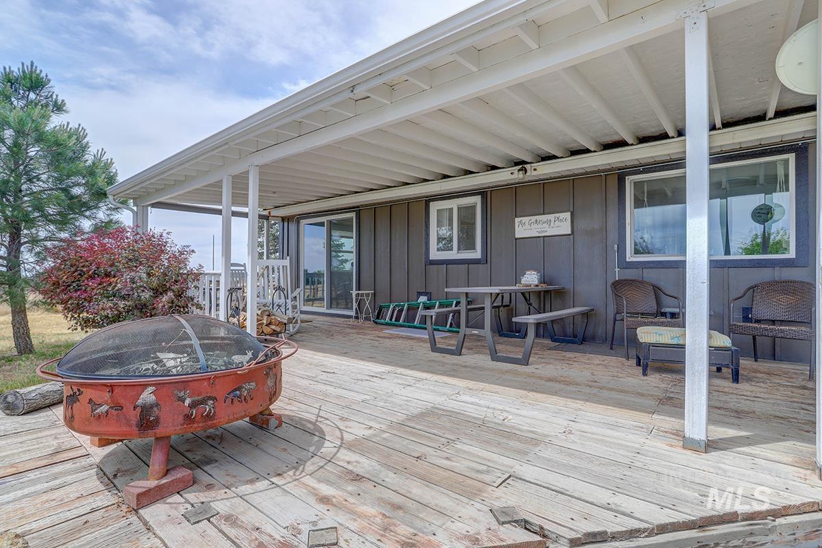9751 Gloria Road Middleton, ID 83644 - Photo 7 of 42 Spacious wood-finish deck with a covered patio, featuring board and batten siding, multiple windows, and a sliding glass door