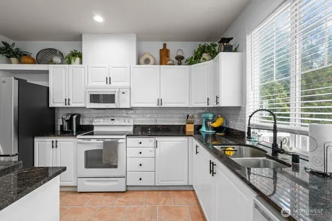 a kitchen with stainless steel appliances granite countertop a sink a stove a refrigerator and cabinets