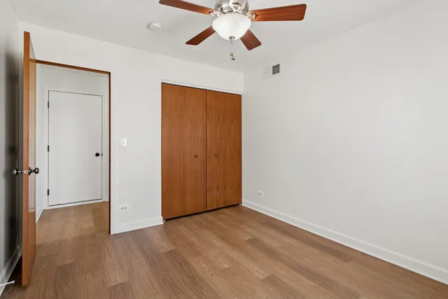 an empty room with wooden floor ceiling fan and window