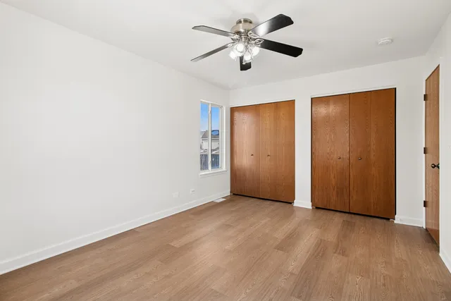an empty room with wooden floor chandelier fan and closet area