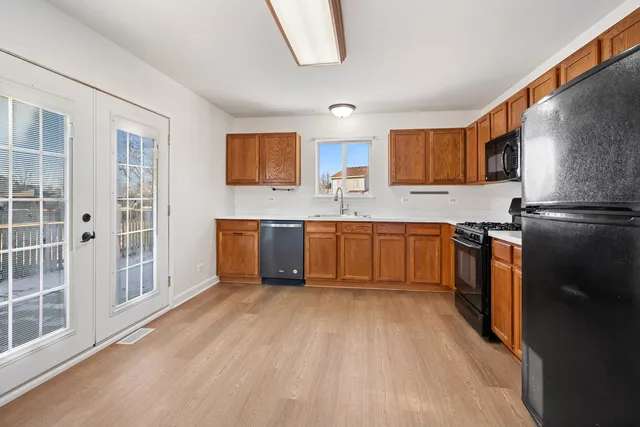 a kitchen with stainless steel appliances granite countertop a stove a sink dishwasher a refrigerator and white cabinets with wooden floor