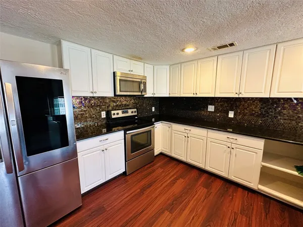 a kitchen with stainless steel appliances wooden floors and wooden cabinets