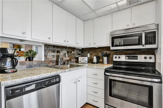 a kitchen with granite countertop white cabinets and stainless steel appliances