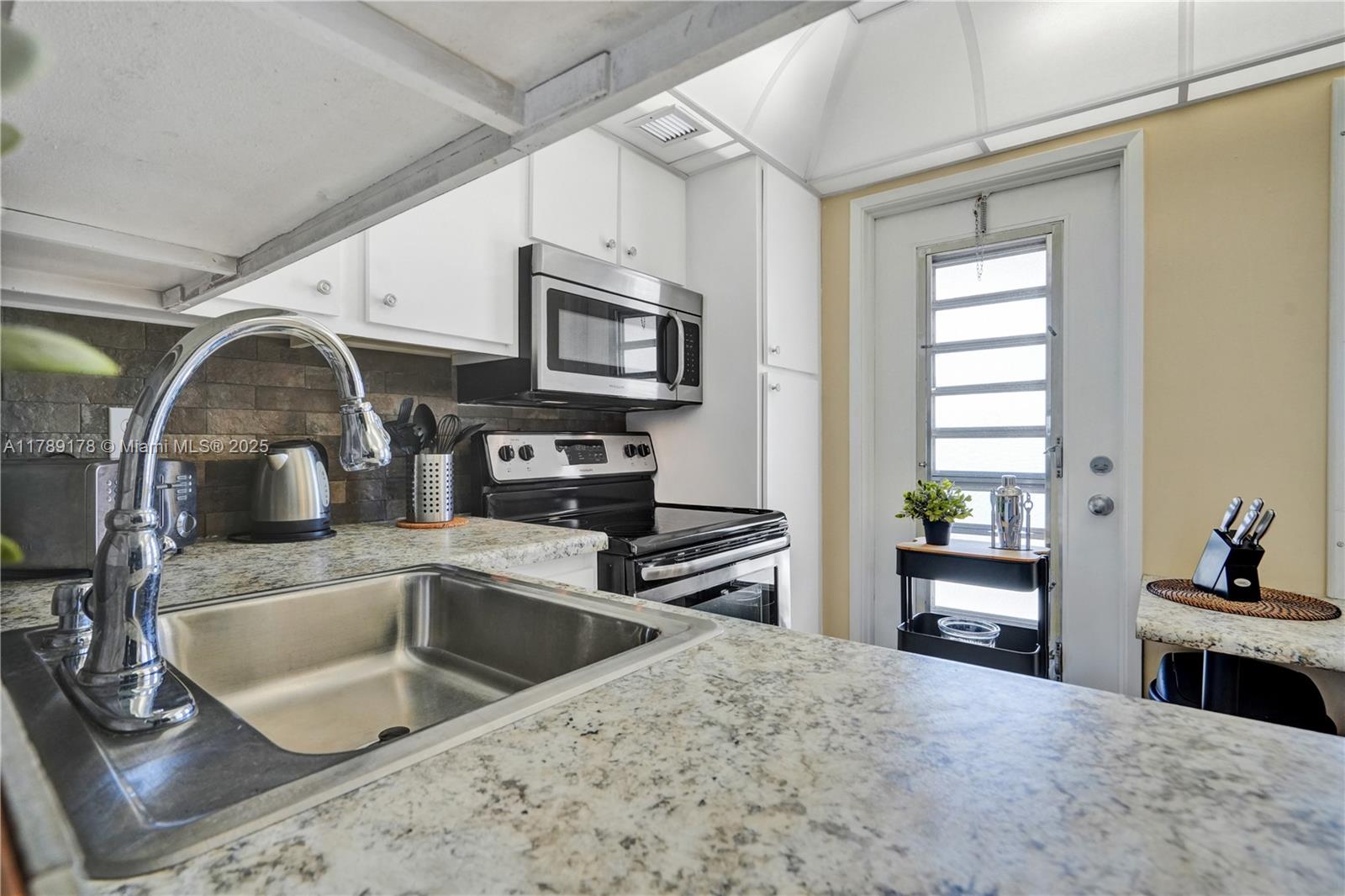 2671 South Course Drive, Unit 409 Pompano Beach, FL 33069 - Photo 23 of 45 a kitchen with stainless steel appliances granite countertop a sink a stove and a refrigerator