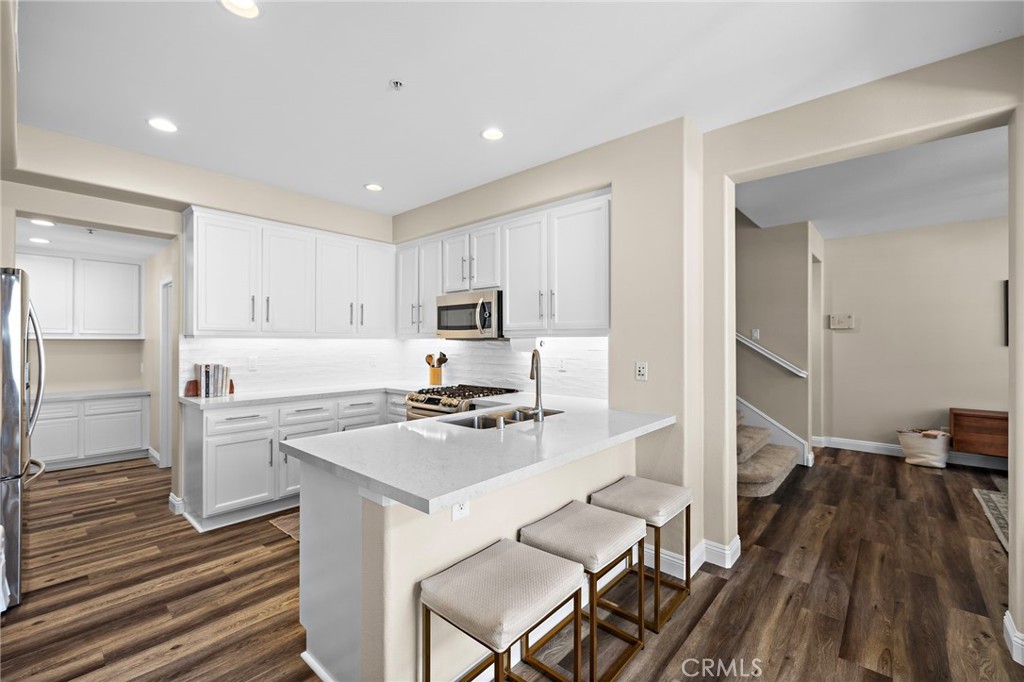 71 Sklar Street Ladera Ranch, CA 92694 - Photo 10 of 55 a kitchen with a refrigerator a stove and white cabinets with wooden floor
