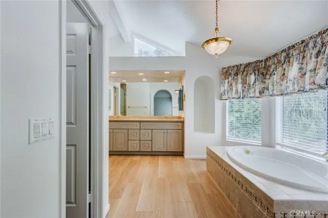 a bathroom with a granite countertop sink a large mirror and a bathtub next to a window