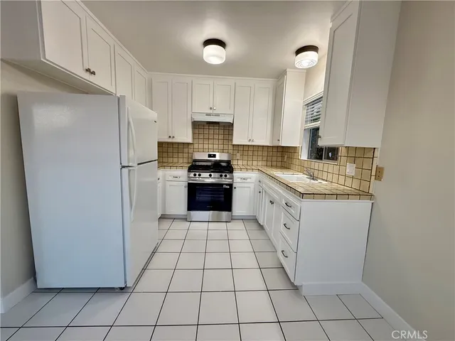 a kitchen with a refrigerator and white cabinets