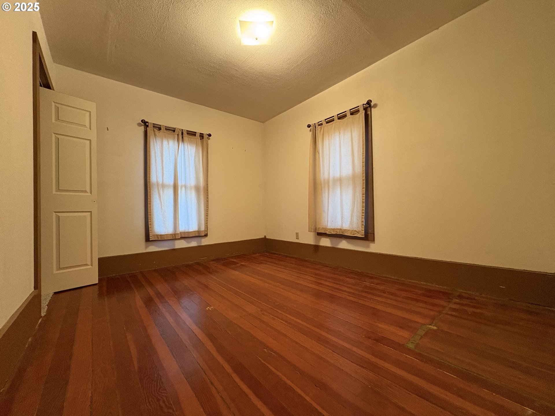 430 West Water Street Stayton, OR 97383 - Photo 22 of 42 an empty room with wooden floor and windows