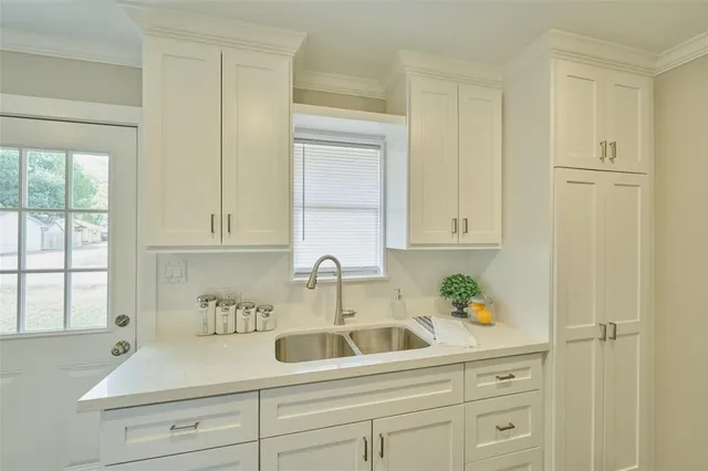a kitchen with white cabinets and sink
