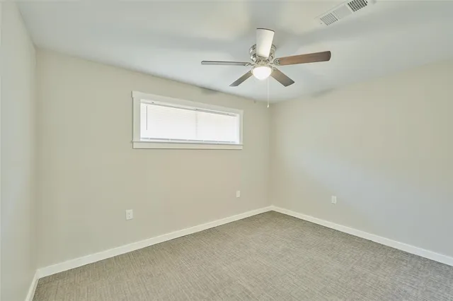 an empty room with a window and a fan