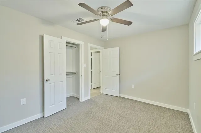 an empty room with a ceiling fan and a shower