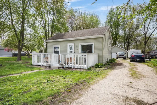 a white house that has a small yard and large trees