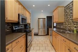 a kitchen with stainless steel appliances granite countertop a refrigerator a stove and a sink