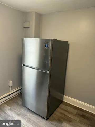 a view of a refrigerator in kitchen and an empty room