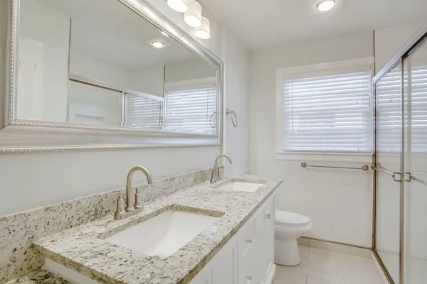 a bathroom with a granite countertop sink a toilet and a mirror
