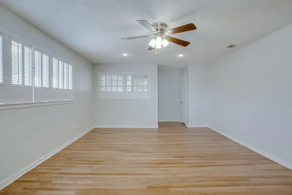 a view of an empty room with wooden floor and a window