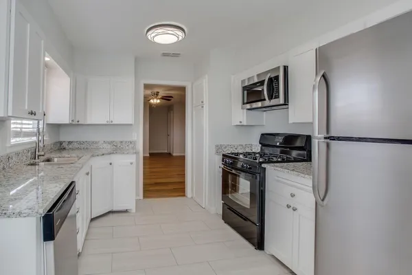 a kitchen with stainless steel appliances granite countertop a stove top oven a sink and a refrigerator