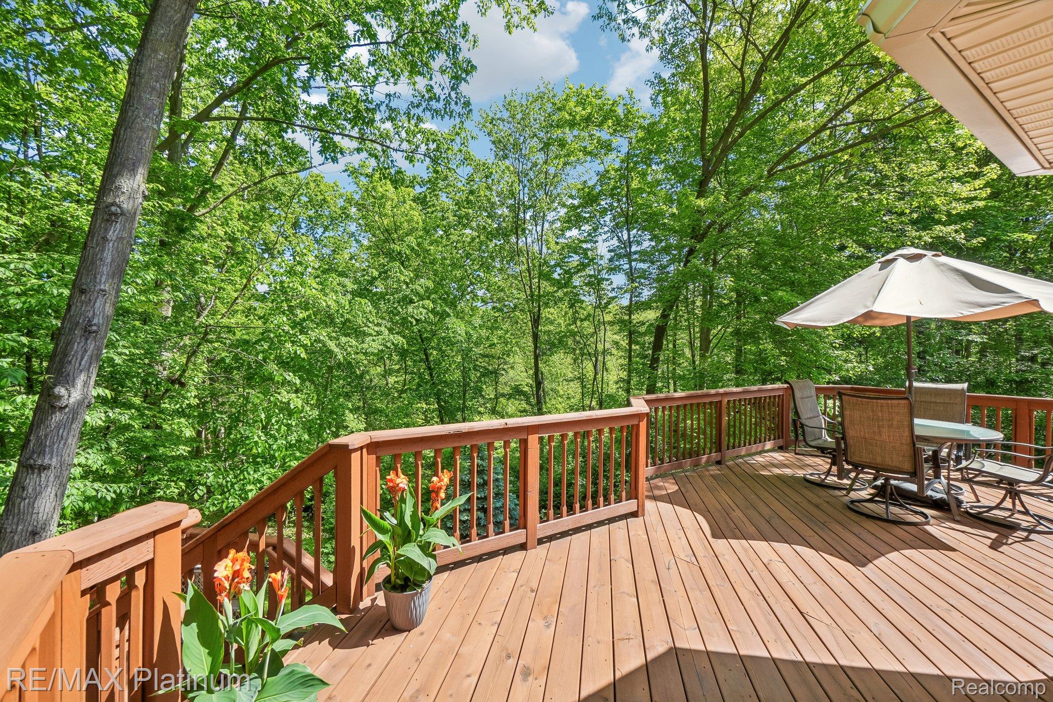 2260 Moorland's View Howell, MI 48855 - Photo 2 of 40 Expansive wood-finish deck with ample space for outdoor furnishing, surrounded by lush mature trees
