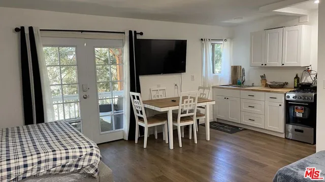 a kitchen with stainless steel appliances a dining table chairs and wooden floor