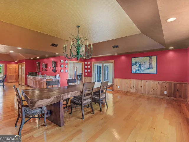 a dining hall with stainless steel appliances kitchen island granite countertop a table chairs and a chandelier