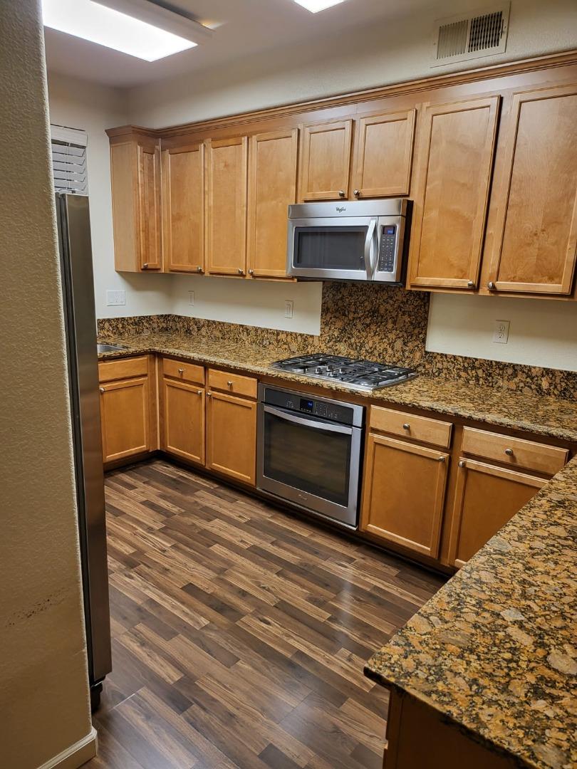 4708 Norris Canyon Road, Unit 203 San Ramon, CA 94583 - Photo 7 of 27 a kitchen with kitchen island granite countertop wooden cabinets and a stove