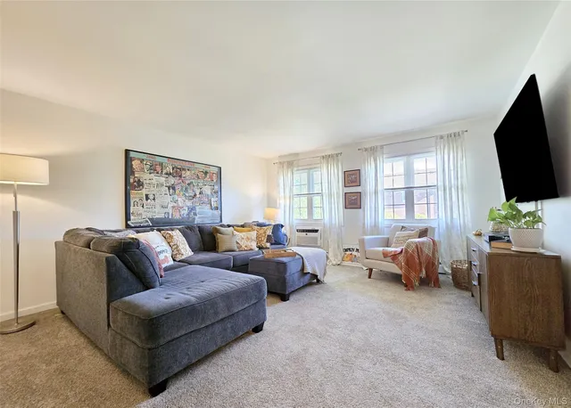 a living room with furniture a flat screen tv and a large window