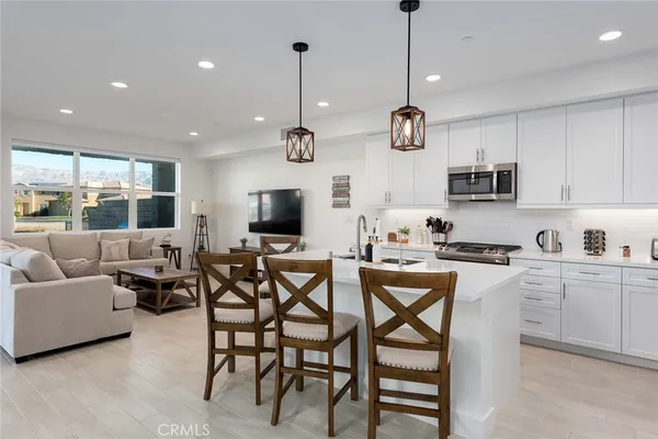 a view of kitchen with stainless steel appliances granite countertop dining table chairs sink and cabinets