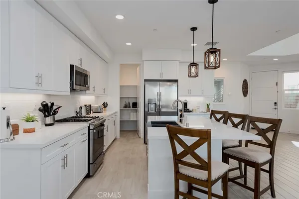 a kitchen with stainless steel appliances kitchen island granite countertop a sink a stove a table and chairs