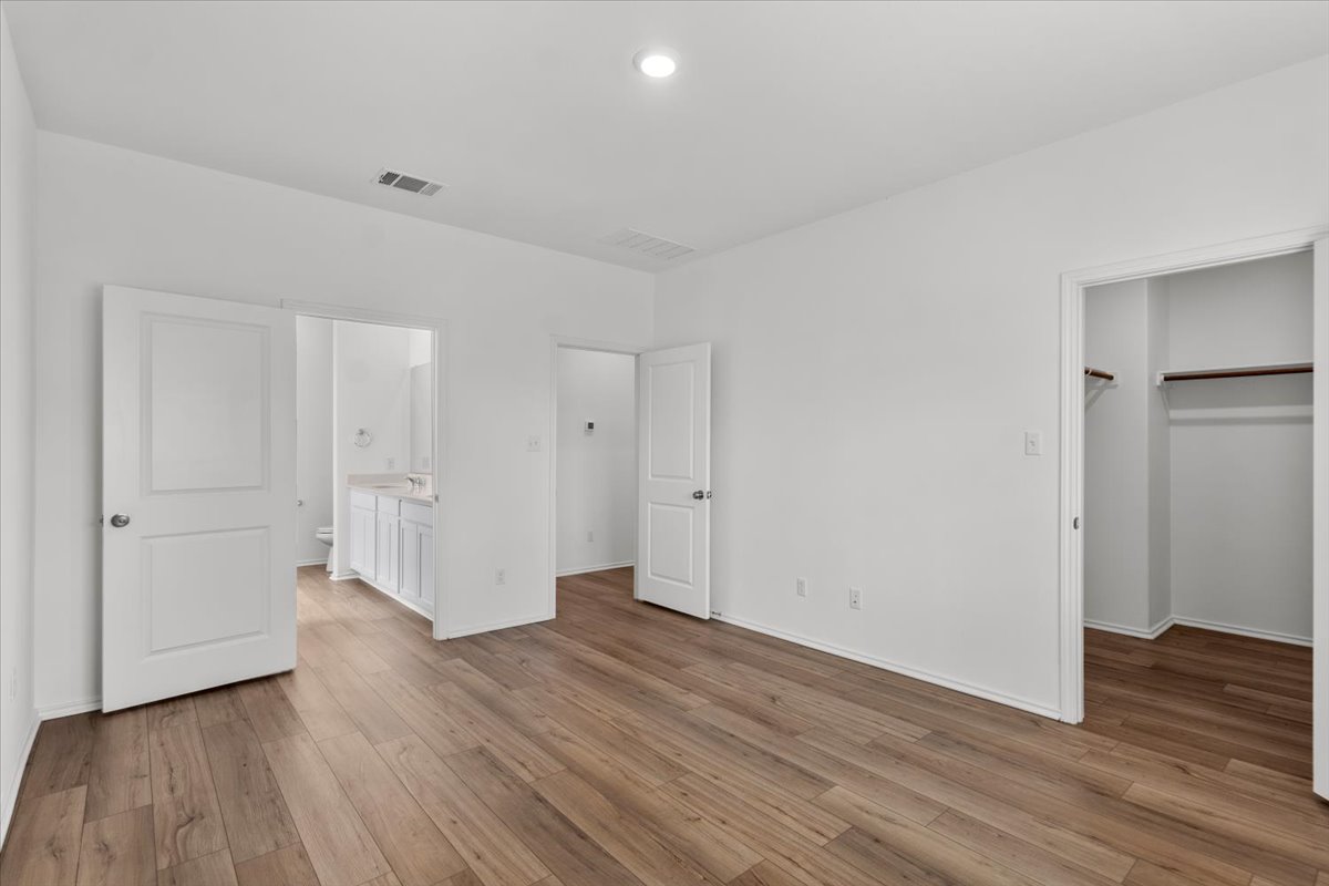 448 Perfect World Loop Jarrell, TX 76537 - Photo 26 of 40 A naturally illuminated bedroom offers hardwood-style flooring and direct access to a private bathroom and closet.