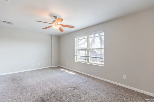 an empty room with windows and fan chandelier fan