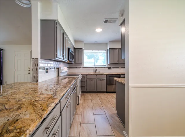 a kitchen with stainless steel appliances granite countertop a stove a sink and a refrigerator