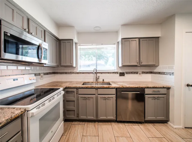 a kitchen with stainless steel appliances granite countertop a sink and stove top oven