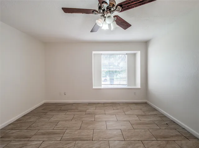 an empty room with a chandelier fan and windows