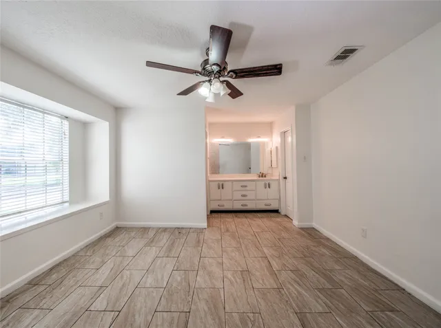 a view of an empty room with a window and a kitchen view