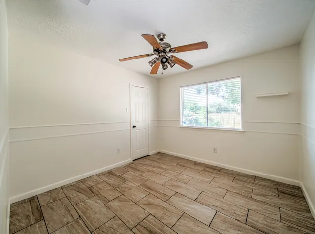 an empty room with wooden floor fan and windows