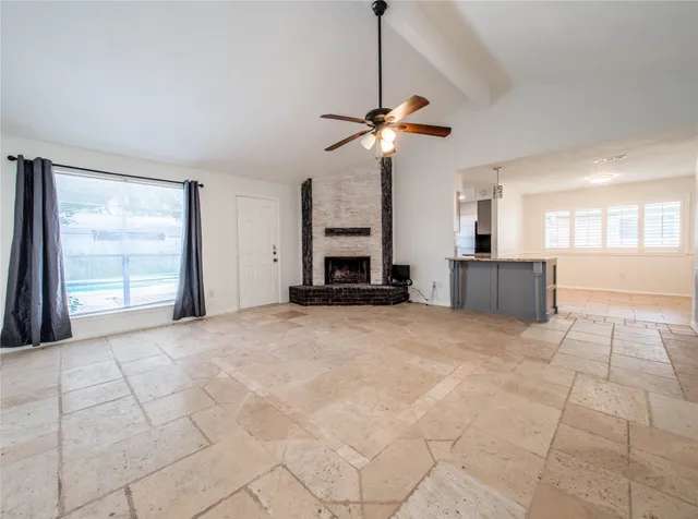 a view of an empty room with a window and a kitchen