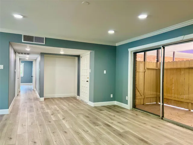 a view of an empty room with window and wooden floor