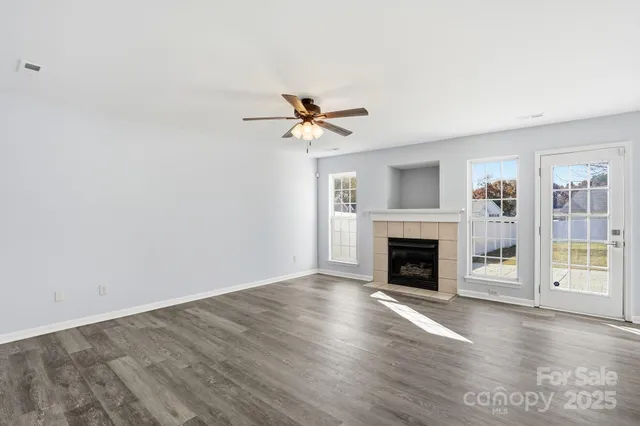 a view of an empty room with a kitchen and a fireplace